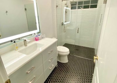 Remodeled Bathroom with tiled floor and new vanity with Illuminated Mirror