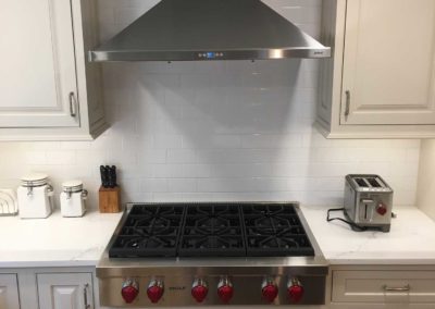 Kitchen remodel by Moorestown NJ construction company includes stainless steel gas range and vent hood