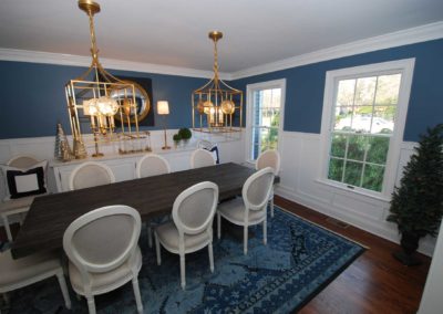 Dual gold chandeliers installed by local construction company make a statement in this elegant wainscot lined formal dining room
